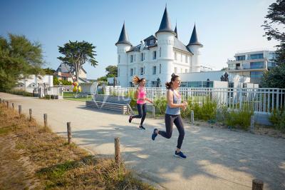 Salle de restaurant lumineuse avec tables dressées, chaises violettes, luminaires dorés et grandes baies vitrées.