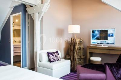 Salle de restaurant lumineuse avec tables dressées, chaises violettes, luminaires dorés et grandes baies vitrées.