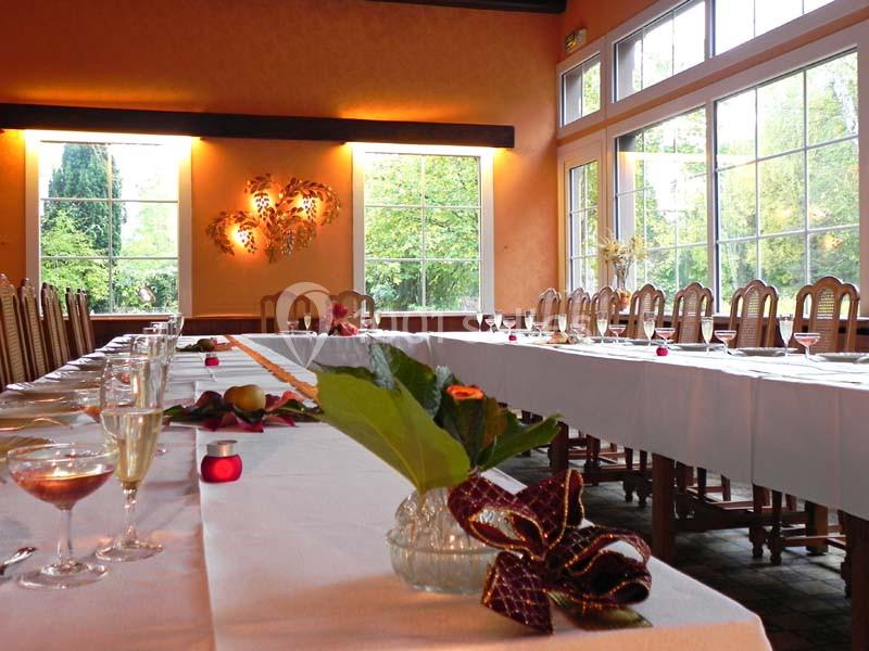 Salle de réception lumineuse avec de grandes baies vitrées, tables dressées et décorations élégantes.
