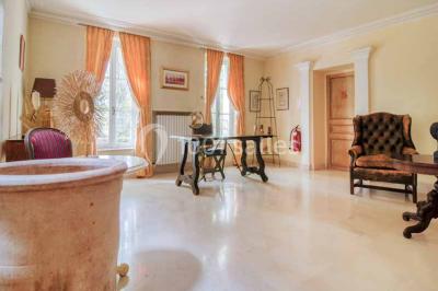 Salle de bain avec baignoire encastrée, lavabo sur meuble en marbre beige et fenêtre laissant entrer la lumière naturelle.