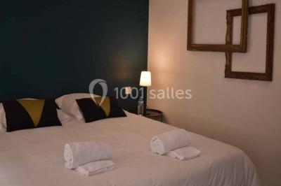 Salle de bain avec baignoire encastrée, lavabo sur meuble en marbre beige et fenêtre laissant entrer la lumière naturelle.