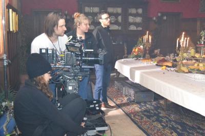 Une équipe de tournage filme une table dressée avec des plats et des chandeliers dans une pièce décorée.