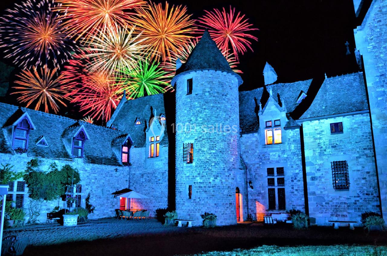 Feu d'artifice coloré illuminant un château en pierre dans la nuit.