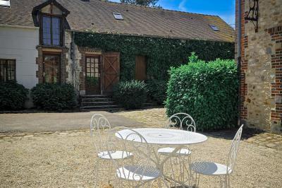 Jardin verdoyant avec pelouse bien entretenue, arbres et arbustes sous un ciel bleu dégagé.
