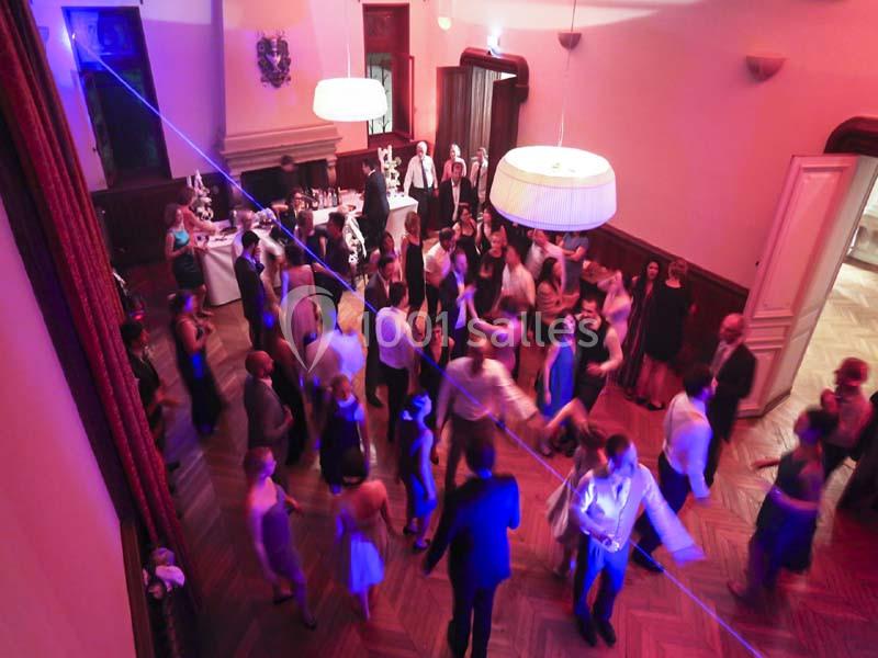 Groupe de personnes dans une salle éclairée, dansant et socialisant lors d'un événement festif.
