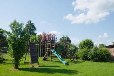 Salle de réception avec murs en briques, poutres apparentes, tables hautes et chaises pliantes sous des lampes suspendues.