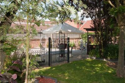 Salle de réception avec murs en briques, poutres apparentes, tables hautes et chaises pliantes sous des lampes suspendues.
