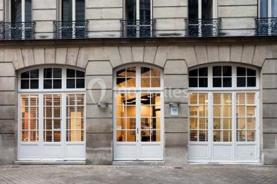 Salle de réunion avec table blanche, chaises rouges, écran mural et éclairage au plafond.