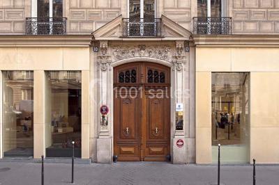 Salle de réunion avec table blanche, chaises rouges, écran mural et éclairage au plafond.