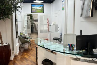 Salle de réunion avec table blanche, chaises rouges, écran mural et éclairage au plafond.