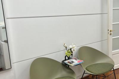 Salle de réunion avec table blanche, chaises rouges, écran mural et éclairage au plafond.