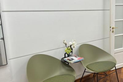 Salle de réunion avec table blanche, chaises rouges, écran mural et éclairage au plafond.