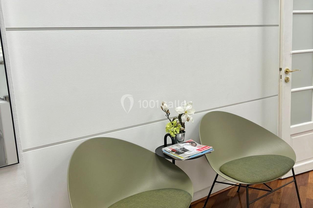 Deux fauteuils verts autour d'une petite table avec des magazines et des fleurs, dans un espace nommé ’Espace George V’.