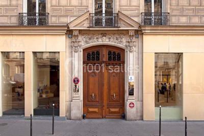 Salle de réunion avec table blanche, chaises rouges, écran mural et éclairage au plafond.