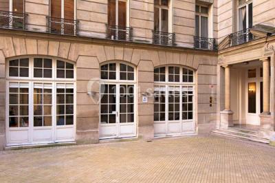 Salle de réunion avec table blanche, chaises rouges, écran mural et éclairage au plafond.