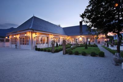 Vue aérienne d'un domaine entouré de verdure, avec des montagnes en arrière-plan sous un ciel dégagé.