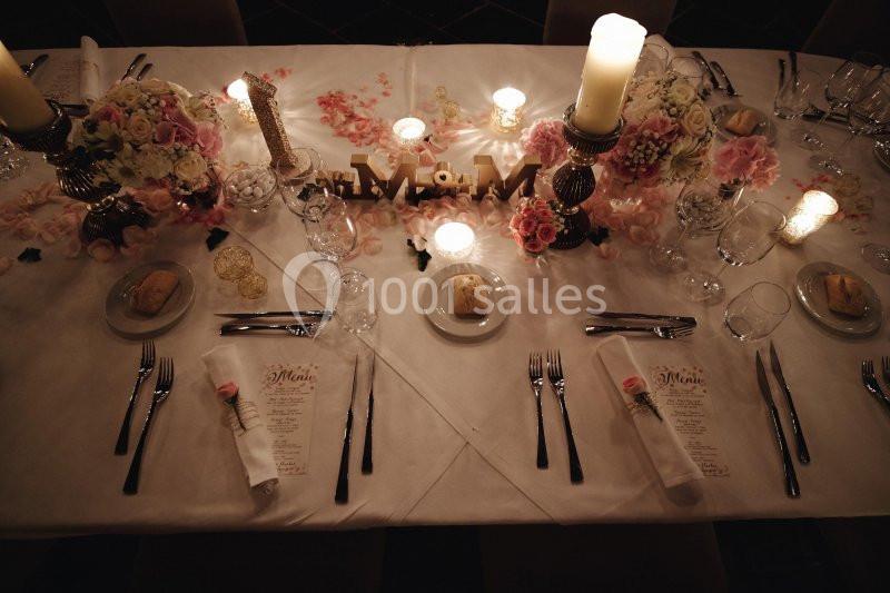 Table élégamment dressée avec bougies, fleurs, menus et assiettes disposées pour un dîner formel.