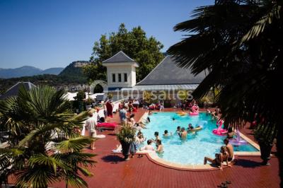 Vue aérienne d'un domaine entouré de verdure, avec des montagnes en arrière-plan sous un ciel dégagé.