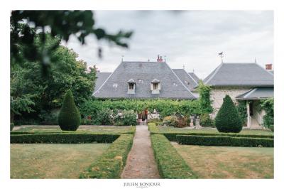 Vue aérienne d'un domaine entouré de verdure, avec des montagnes en arrière-plan sous un ciel dégagé.