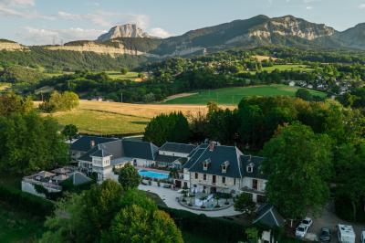 Vue aérienne d'un domaine entouré de verdure, avec des montagnes en arrière-plan sous un ciel dégagé.