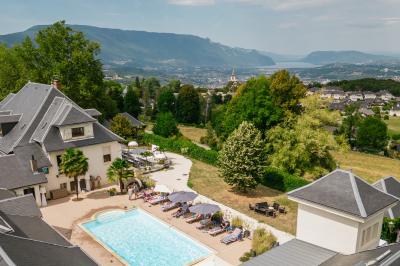 Vue aérienne d'un domaine entouré de verdure, avec des montagnes en arrière-plan sous un ciel dégagé.