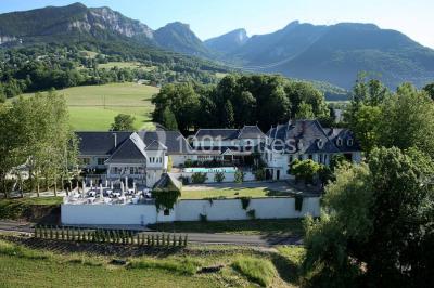 Vue aérienne d'un domaine entouré de verdure, avec des montagnes en arrière-plan sous un ciel dégagé.