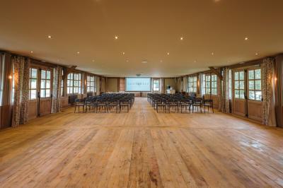 Intérieur d'un sauna en bois en forme de tonneau avec vue sur un paysage verdoyant et des montagnes au loin.