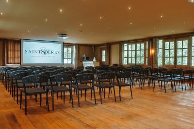 Intérieur d'un sauna en bois en forme de tonneau avec vue sur un paysage verdoyant et des montagnes au loin.