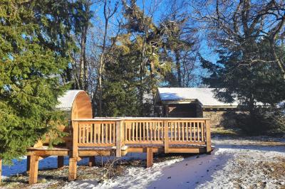 Intérieur d'un sauna en bois en forme de tonneau avec vue sur un paysage verdoyant et des montagnes au loin.