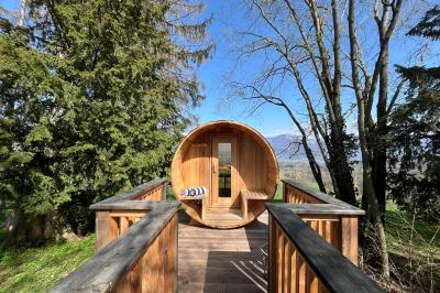 Intérieur d'un sauna en bois en forme de tonneau avec vue sur un paysage verdoyant et des montagnes au loin.