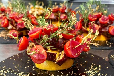 Vue aérienne d'un centre équestre entouré de végétation, avec la mer et des îles en arrière-plan.