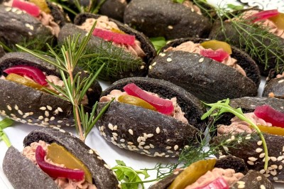 Vue aérienne d'un centre équestre entouré de végétation, avec la mer et des îles en arrière-plan.