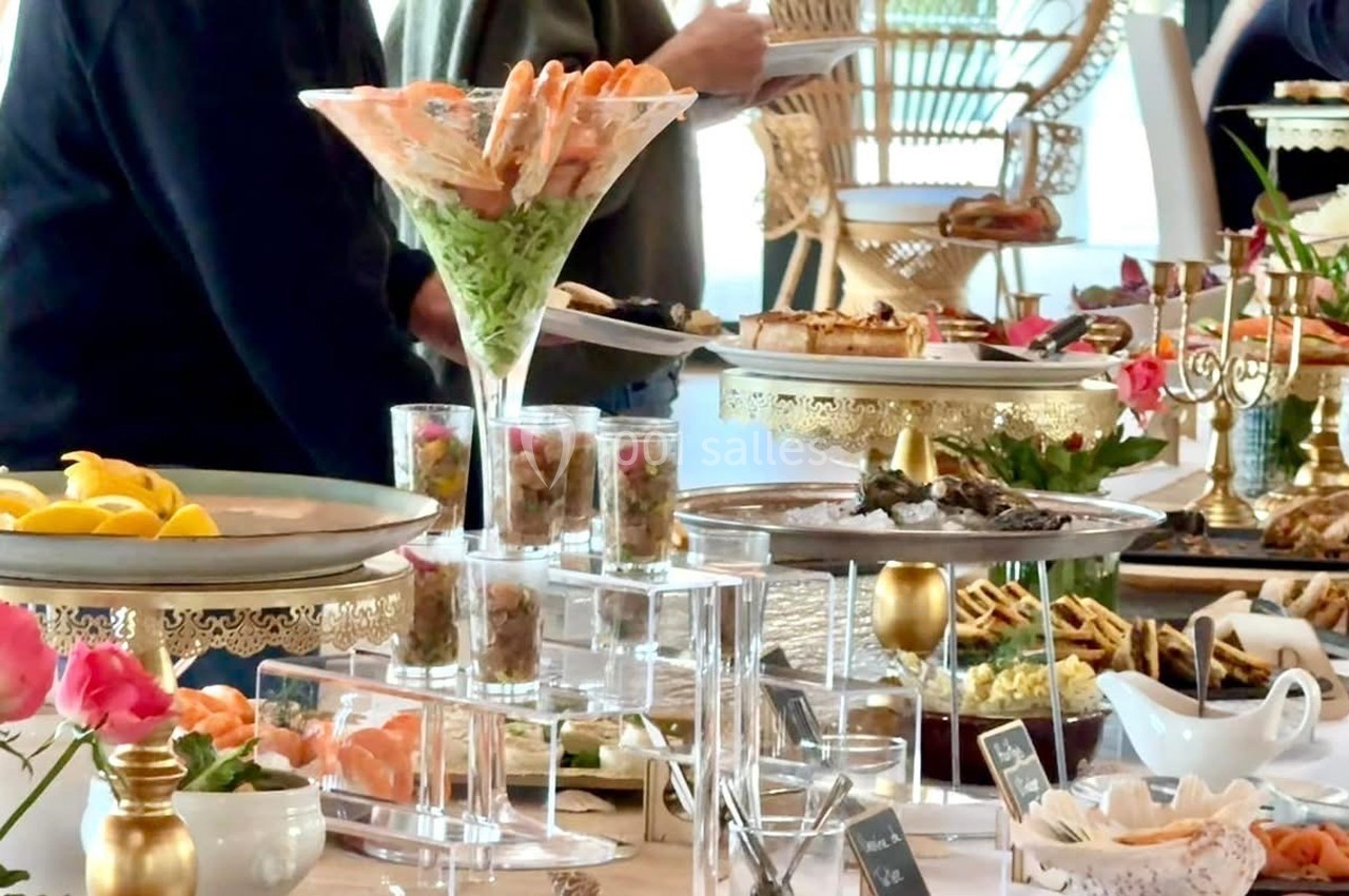 Buffet varié avec fruits de mer, verrines, pâtisseries et décorations élégantes sur une table bien garnie.