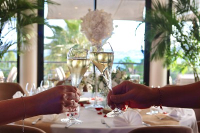 Salle de réception élégamment décorée avec des tables rondes dressées, nappes blanches et centres de table floraux.