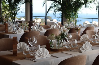 Salle de réception élégamment décorée avec des tables rondes dressées, nappes blanches et centres de table floraux.