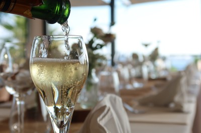 Salle de réception élégamment décorée avec des tables rondes dressées, nappes blanches et centres de table floraux.