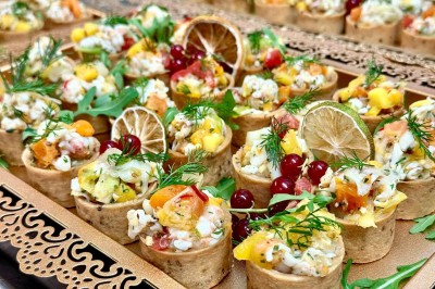 Salle de réception élégamment décorée avec des tables rondes dressées, nappes blanches et centres de table floraux.