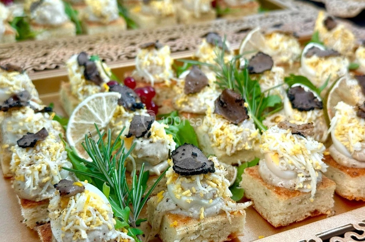 Canapés garnis de mousse, truffes, fromage râpé, herbes fraîches, citron et groseilles rouges sur plateau décoratif.