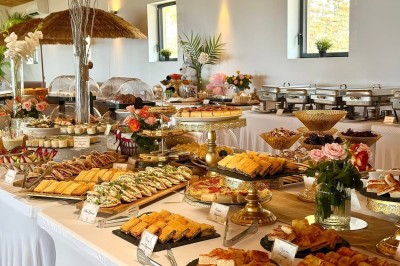 Salle de réception élégamment décorée avec des tables rondes dressées, nappes blanches et centres de table floraux.