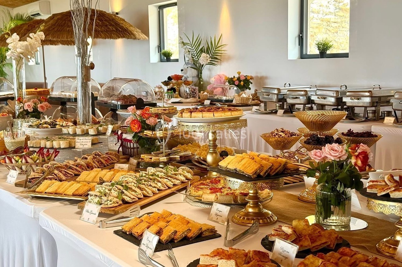 Buffet varié avec plats salés et sucrés disposés sur des tables décorées de fleurs et d'éléments élégants.