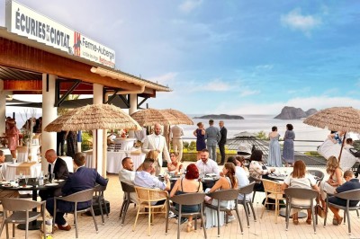 Salle de réception élégamment décorée avec des tables rondes dressées, nappes blanches et centres de table floraux.