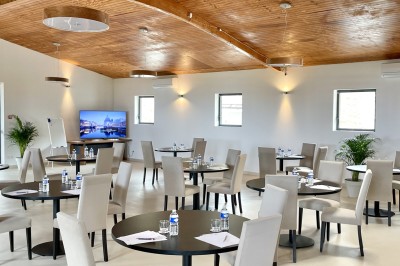 Salle de réception élégamment décorée avec des tables rondes dressées, nappes blanches et centres de table floraux.