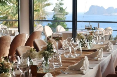 Salle de réception élégamment décorée avec des tables rondes dressées, nappes blanches et centres de table floraux.
