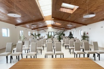 Salle de réception élégamment décorée avec des tables rondes dressées, nappes blanches et centres de table floraux.