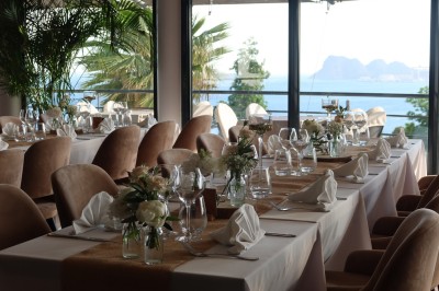 Salle de réception élégamment décorée avec des tables rondes dressées, nappes blanches et centres de table floraux.