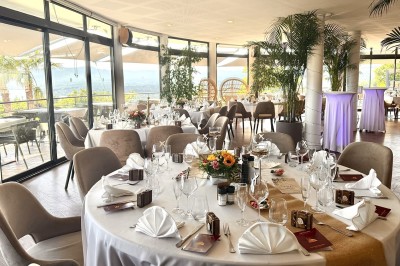 Salle de réception élégamment décorée avec des tables rondes dressées, nappes blanches et centres de table floraux.