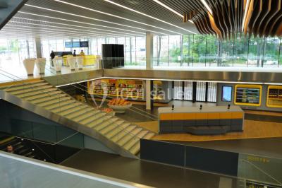 Bâtiment moderne avec façade blanche, toit en surplomb et grandes baies vitrées, entouré de végétation.