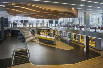 Bâtiment moderne avec façade blanche, toit en surplomb et grandes baies vitrées, entouré de végétation.