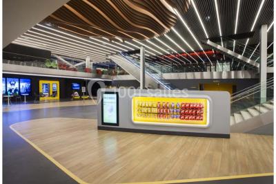 Bâtiment moderne avec façade blanche, toit en surplomb et grandes baies vitrées, entouré de végétation.