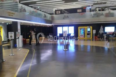 Bâtiment moderne avec façade blanche, toit en surplomb et grandes baies vitrées, entouré de végétation.